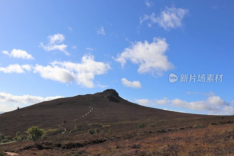 山顶上蓝色的天空中飘浮着白云