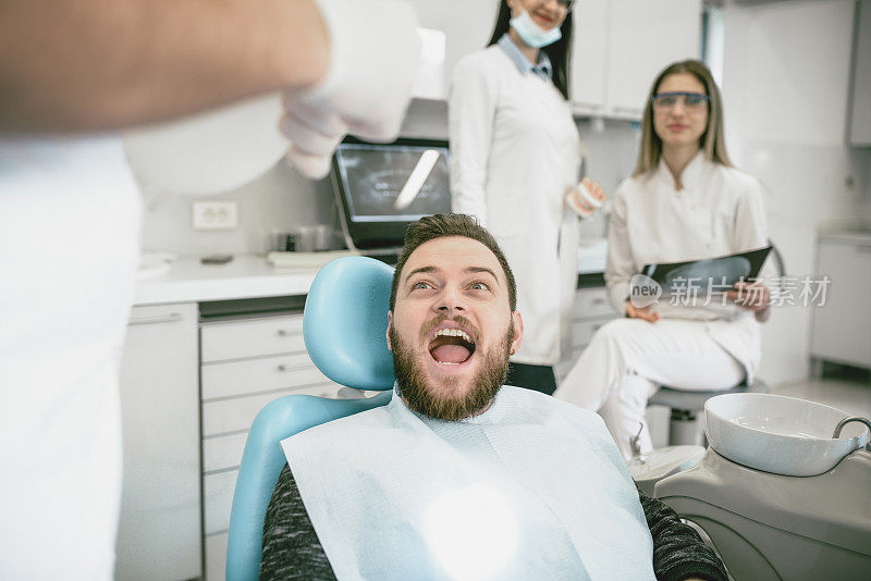 害怕的男性病人张开嘴进行牙齿治疗
