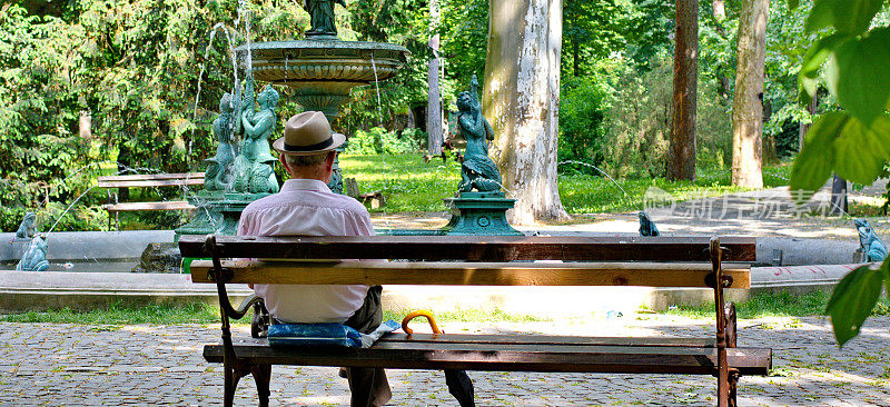 一个孤独的老人坐在公园的长椅上