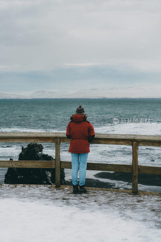 一个女人走在冰岛的黑沙滩上