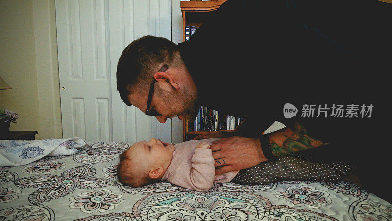 年轻的父亲拥抱，亲吻和慈爱地玩他的小女儿