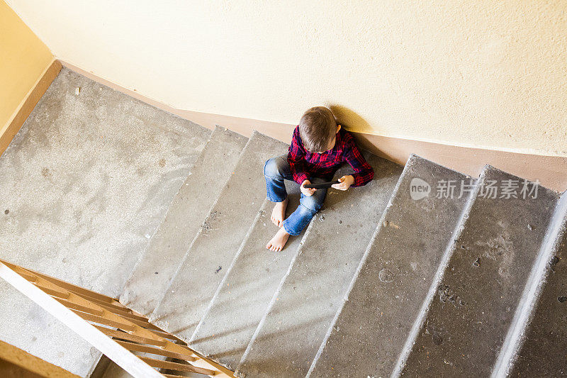 一个孩子在楼梯间打电话。