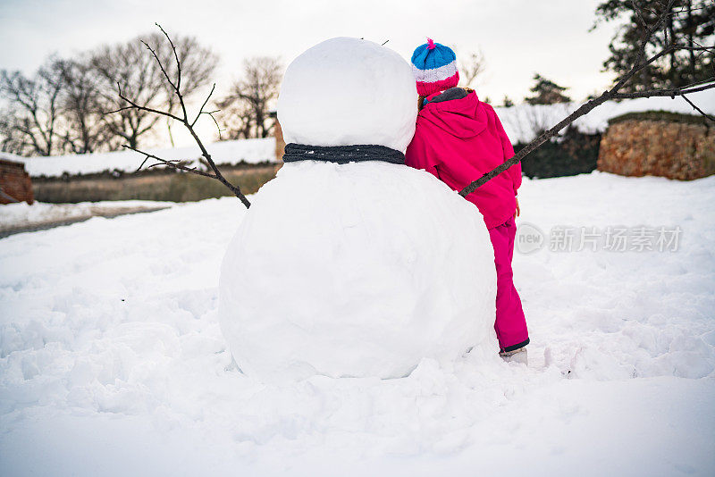 后视图，一个堆着雪人的女孩