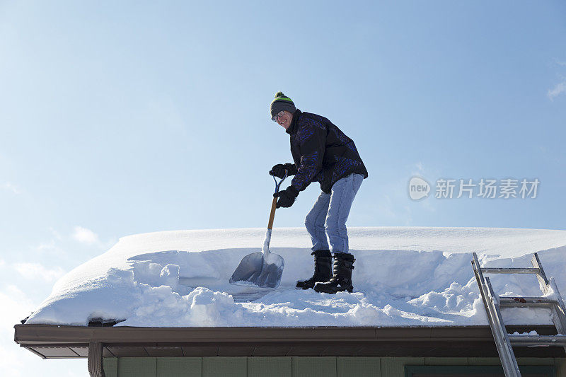 一名男子正在铲屋顶上的积雪