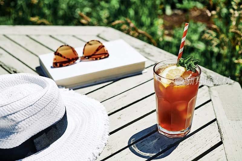 夏日美景，阳光明媚的花园桌上放着柠檬薄荷冰茶。