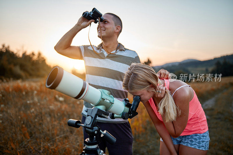 青年男女用望远镜和双筒望远镜看天空。