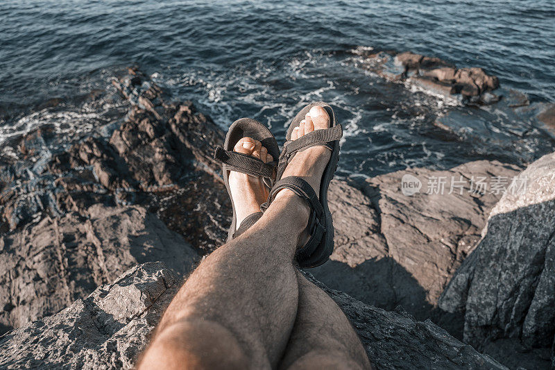 休息。夏日独自旅行者的视频。男游客在岩石上放松，眼前是美丽的海景。股票的照片。