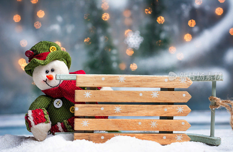 玩具雪人与雪橇和节日照明圣诞背景