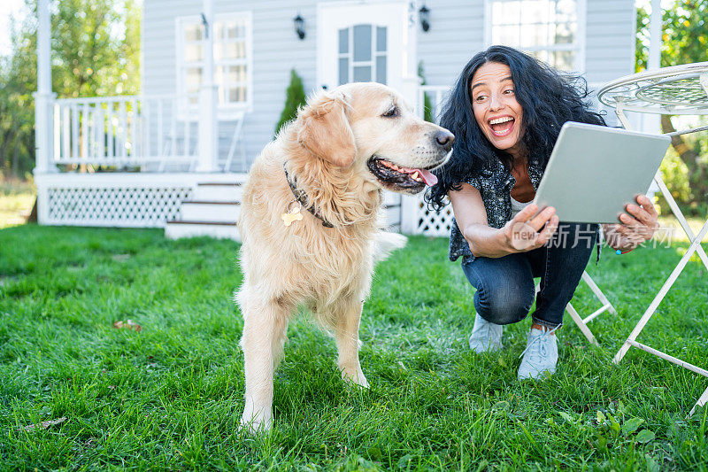 微笑的中年妇女和她的金毛猎犬在前院自拍