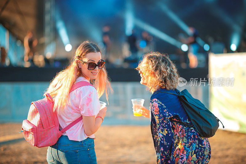 年轻女子与女友在开放的门节日看在相机的肩膀