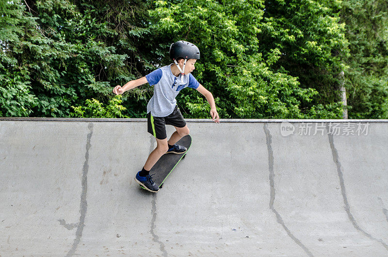 小男孩滑着滑板上斜坡