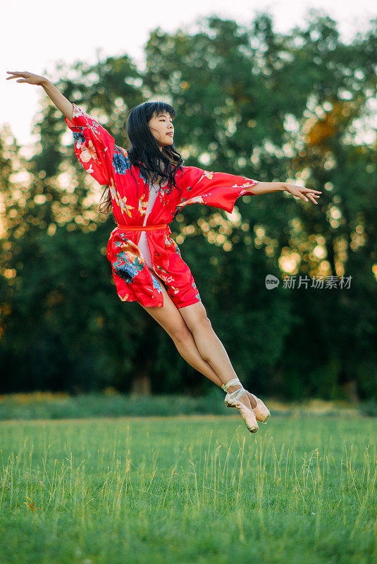 日本芭蕾舞演员在草坪和树的背景上跳。