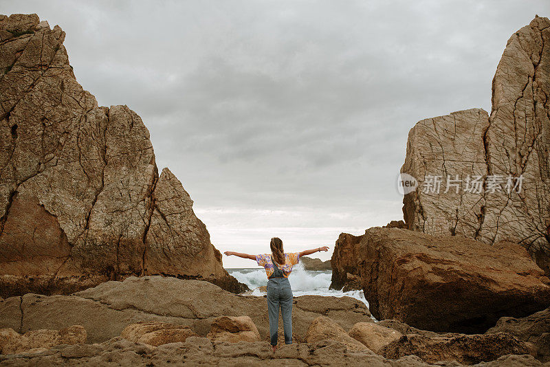 年轻女子在海滩上举起双手