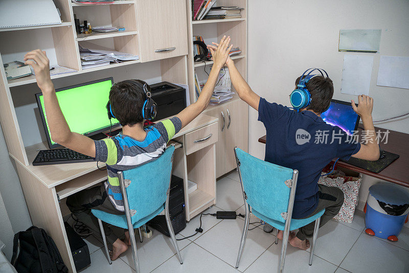 两兄弟在书房玩电脑游戏。