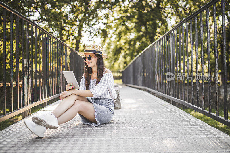 时尚年轻女子放松，使用数字平板电脑和花时间在自然