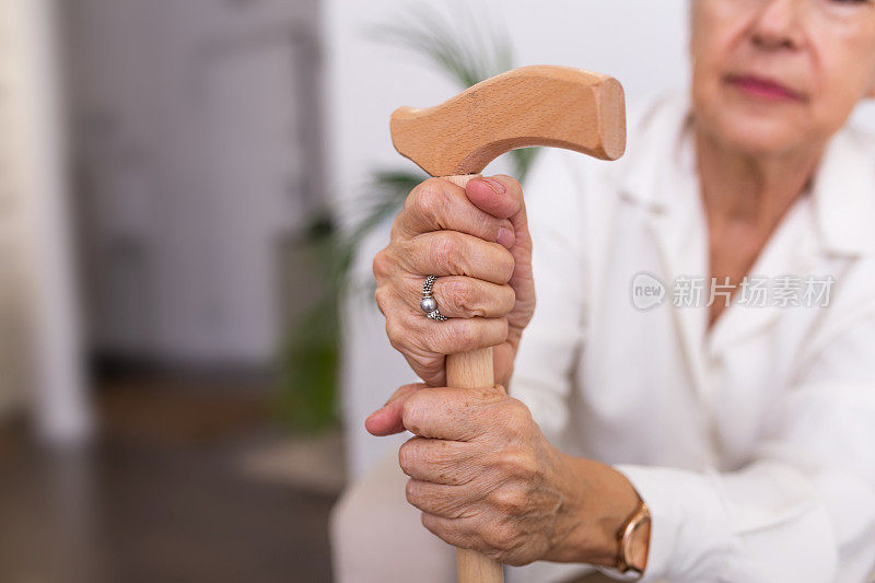 手中拿着拐杖的老妇人，坐在沙发上拄着拐杖的老妇人。一名老年妇女在养老院拄着拐杖的镜头
