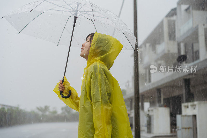 快乐的亚洲华人女子被大雨淋湿