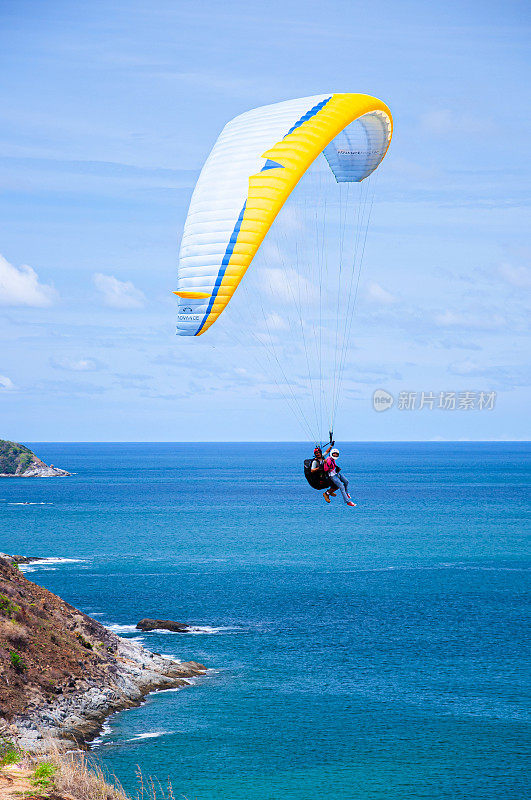 游客们喜欢滑翔伞运动和在蓝色的海面上高空飞行