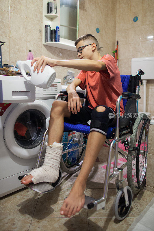 一个坐在轮椅上的青少年在浴室和洗衣机里洗衣服