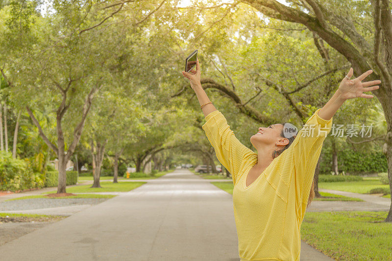 一位年轻的拉丁妇女在美国佛罗里达州迈阿密的珊瑚盖布尔斯街的树冠下享受旅行