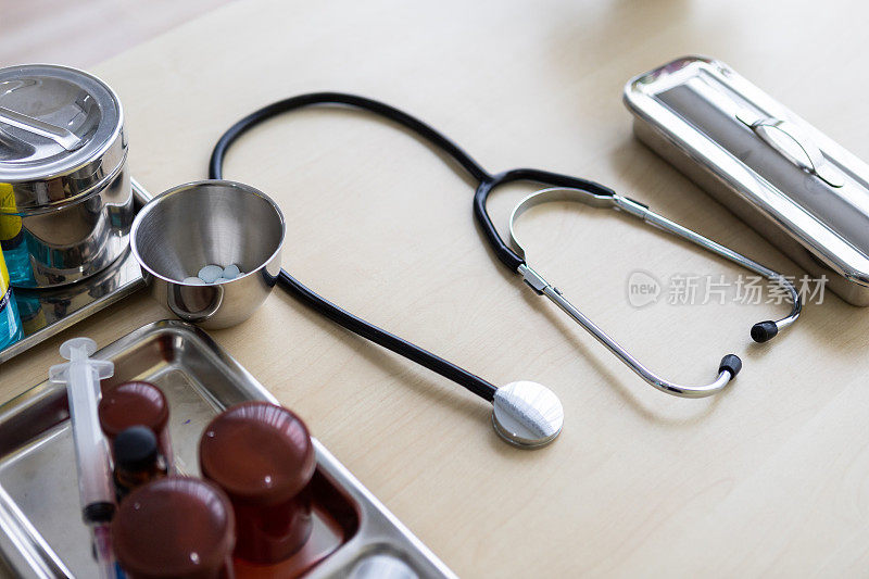 听诊器，小瓶，注射器和医疗瓶不同的药物在手术托盘与医疗设备在木桌背景
