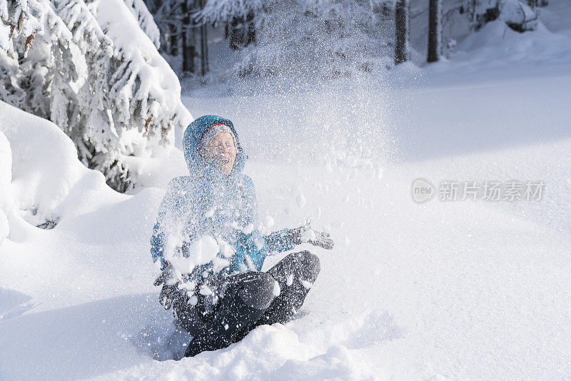 在冬天的森林里，成熟的女人穿着皮大衣向空中抛雪