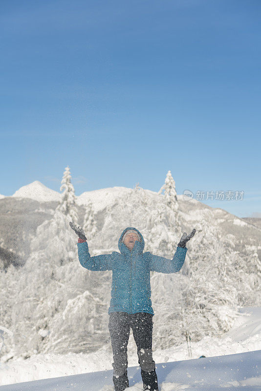 在冬天的森林里，成熟的女人穿着皮大衣向空中抛雪