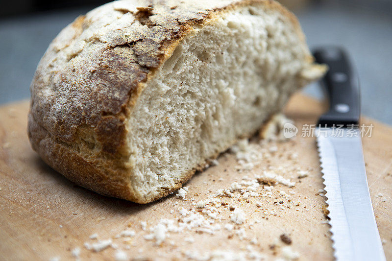一个切片酵母面包和面包屑的特写，与面包刀，在面包板上