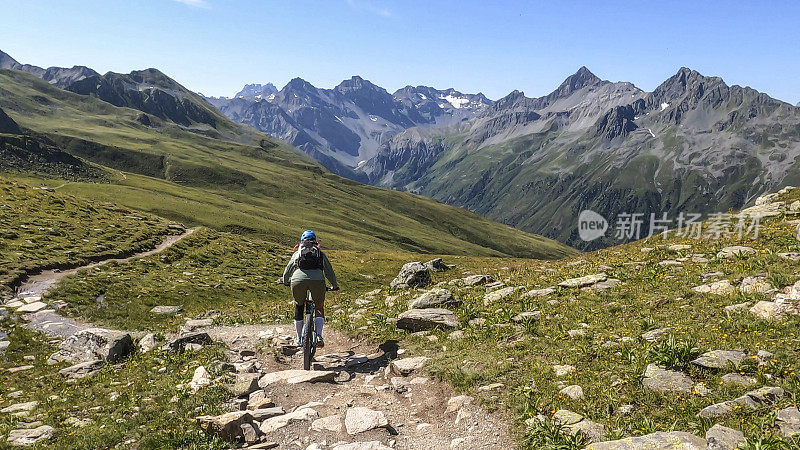 女人沿着阳光明媚的自行车道骑山地车