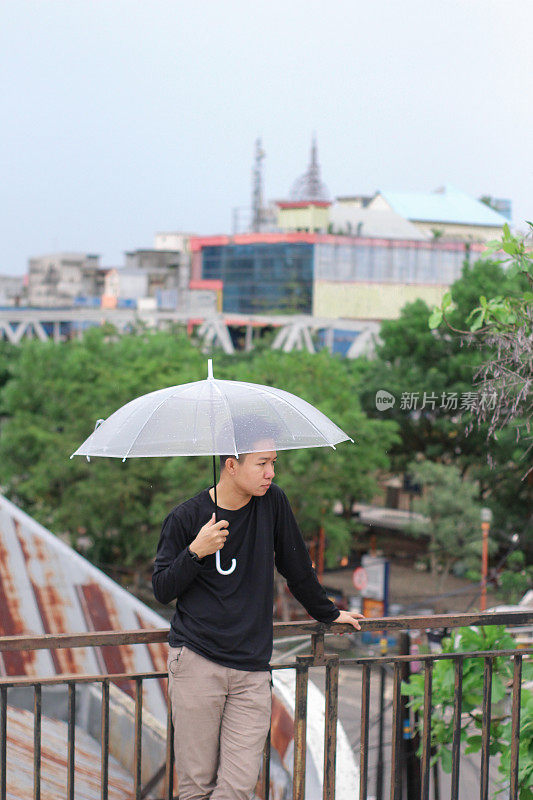 一群年轻人打着伞站在城市公园里