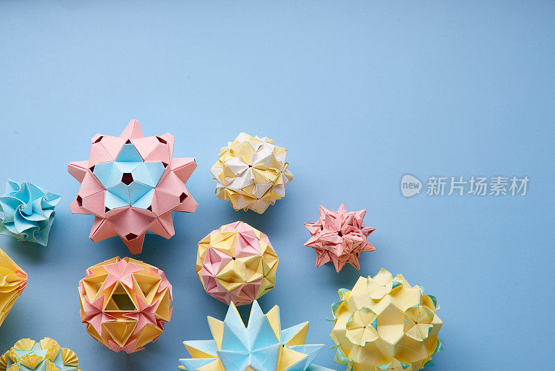 Set的multicolorÂ手工制作modularÂ折纸球或Kusudama孤立在蓝色背景。视觉艺术，几何学，折纸艺术，纸工艺品。俯视图，特写，选择性聚焦，复制空间。
