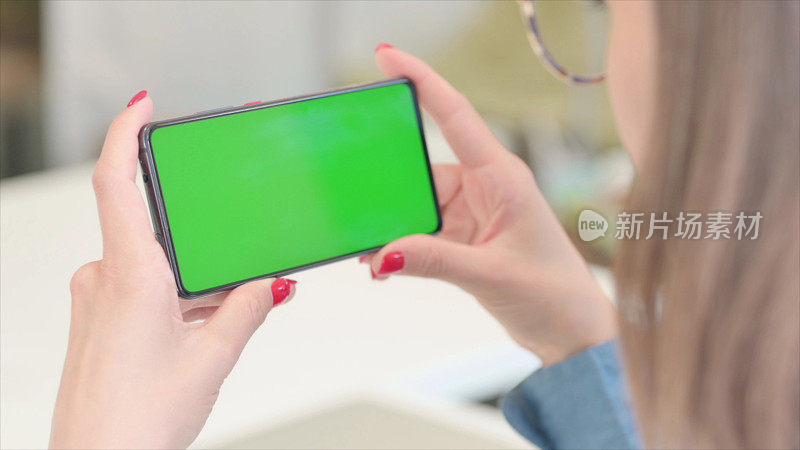 女人拿着绿色色度屏幕的智能手机