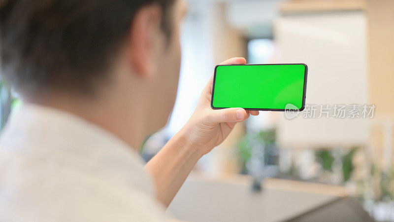 一个年轻人在看带有绿色色度屏幕的智能手机
