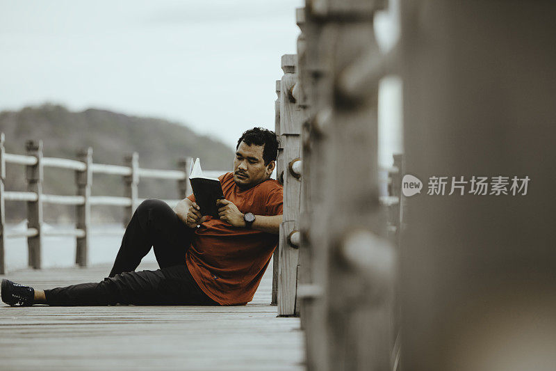 亚洲人在木桥上看书