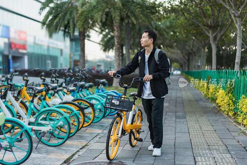 一名亚洲男子准备乘坐共享自行车旅行