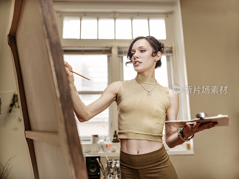 年轻的白人女性艺术家在她的工作室绘画