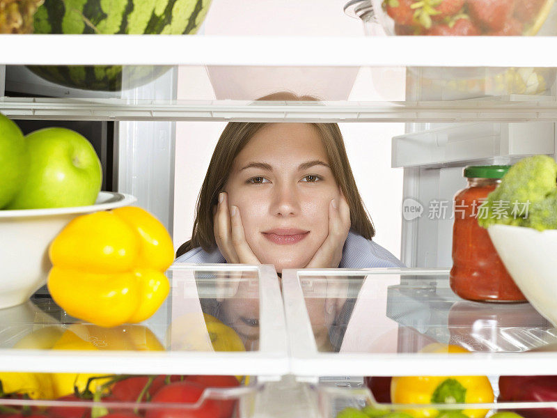一位年轻女士在装满健康食品的冰箱里翻来翻去