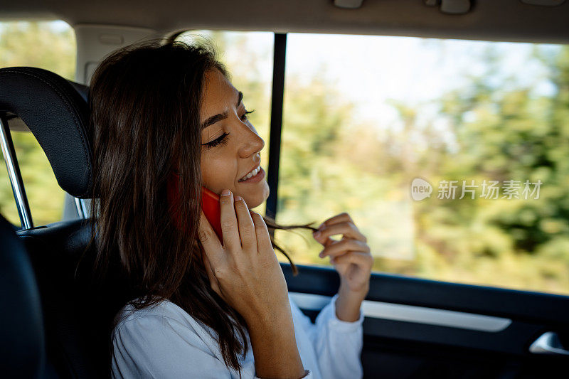 微笑的年轻女子在车里用手机