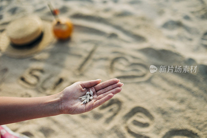 沙滩上拿着贝壳的女人手