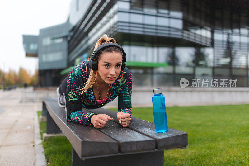 年轻的女运动员在户外长凳上做平板支撑