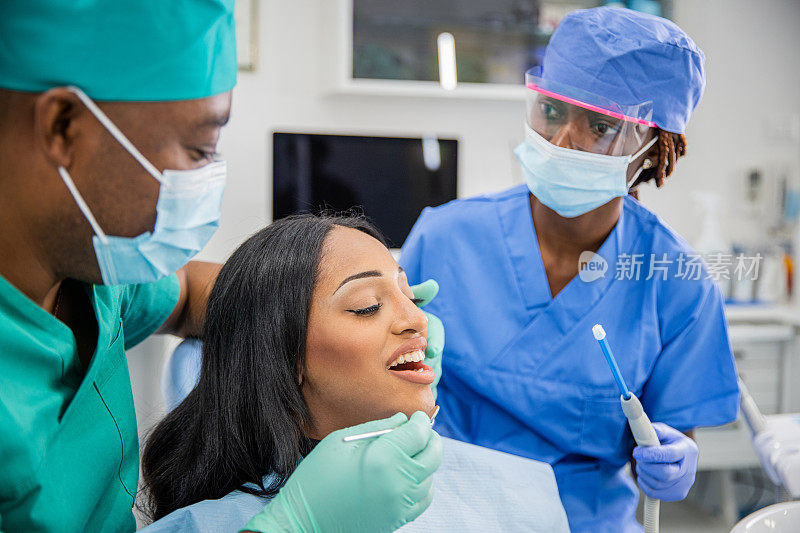 看牙医时张大嘴巴的女孩，工作时的牙医和助手，牙齿健康的概念