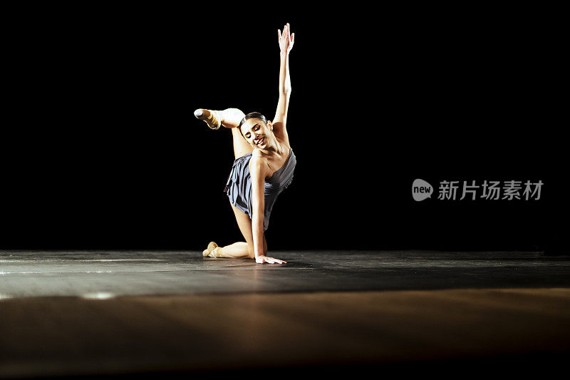 女孩在黑暗的舞台上跳新古典芭蕾