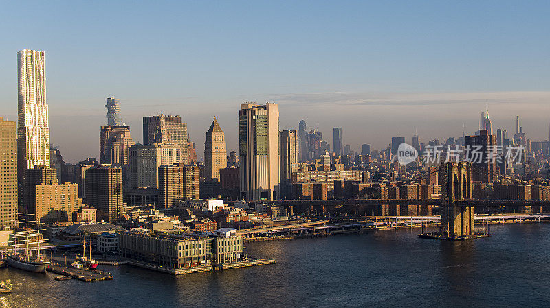 曼哈顿下城滨水区，东河上的华尔街11号码头，远处的布鲁克林大桥和曼哈顿中城的景色。