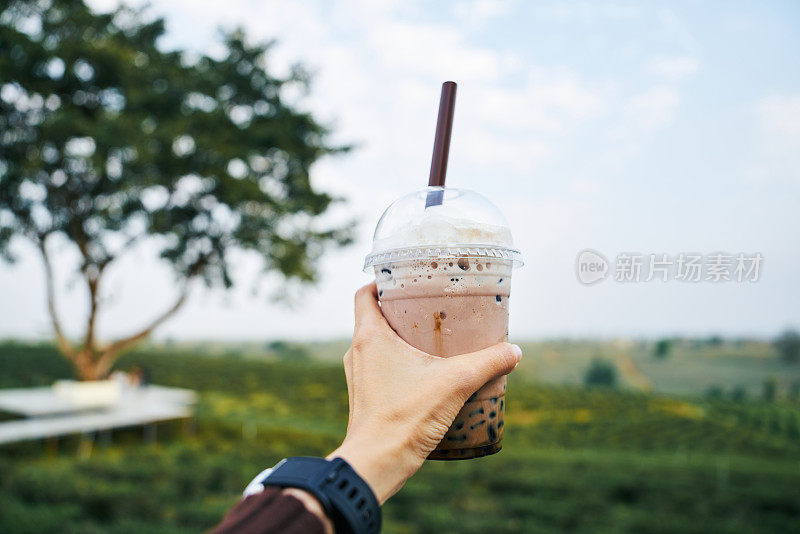 观点女子手拿冰茶牛奶饮料，而旅行度假