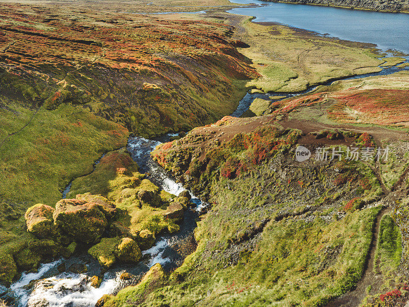 秋天的色彩覆盖了冰岛的景观，瀑布直泻湖中