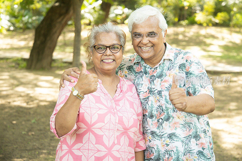 快乐的印度老年夫妇在夏日公园竖起大拇指。享受生活的老人。