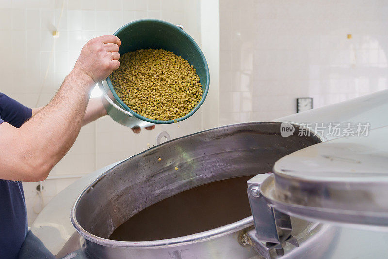 啤酒厂向大桶中添加麦芽的过程，动态模糊，酿造啤酒的蒸汽。背景