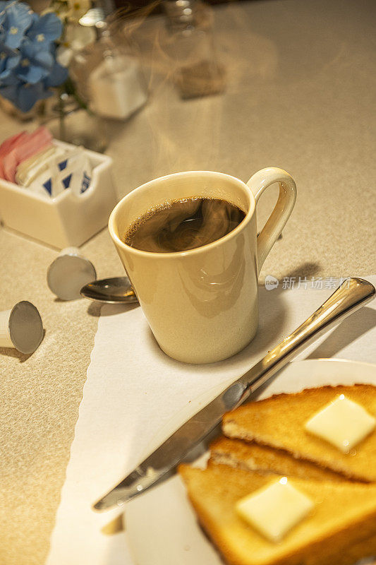 在日出时分的餐厅里，一杯热气腾腾的咖啡和黄油烤面包