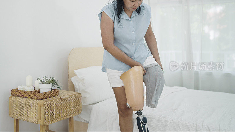 成年亚洲女性截肢者每天醒来后都戴着假肢。残疾人生活中的困难，身体残疾，假肢设备，截肢者概念