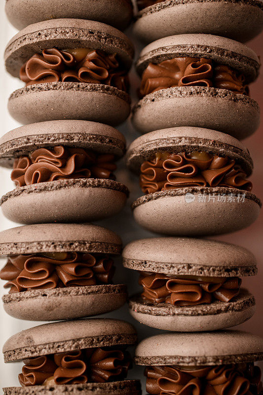 棕色马卡龙的特写照片，奶油巧克力馅垂直地放在两排